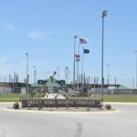 Image of the sign outside area of the Great Bend Sports Complex including flags and field lighting