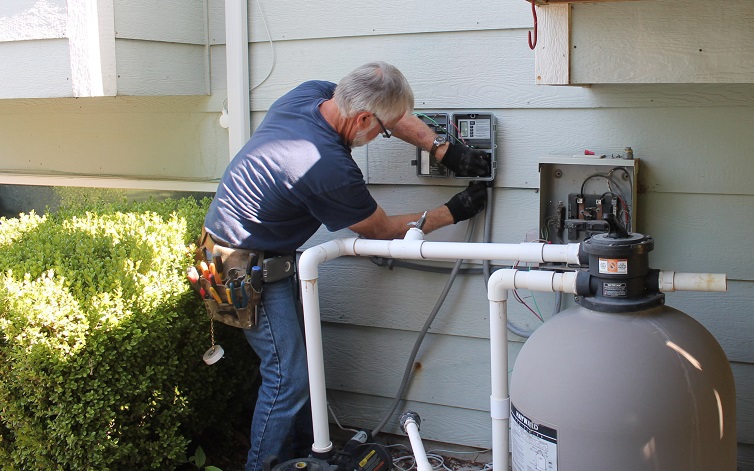 Decker electrician installing electrical timer for pool pump