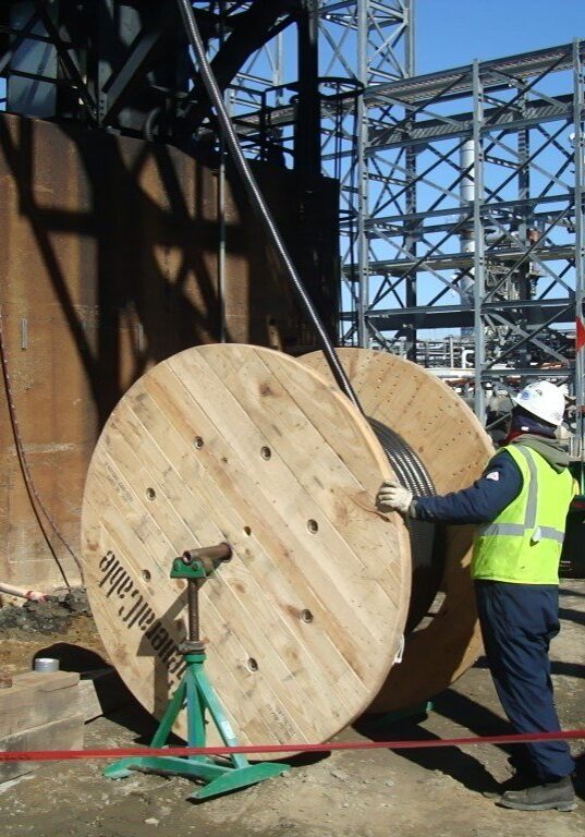 Image of a large coil of piping being handled by a Decker Electric technician at a downstream facility